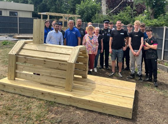 Rainbow Services group members gather around a wooden structure they have built.