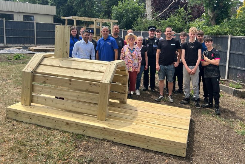 Rainbow Services group members gather around a wooden structure they have built.